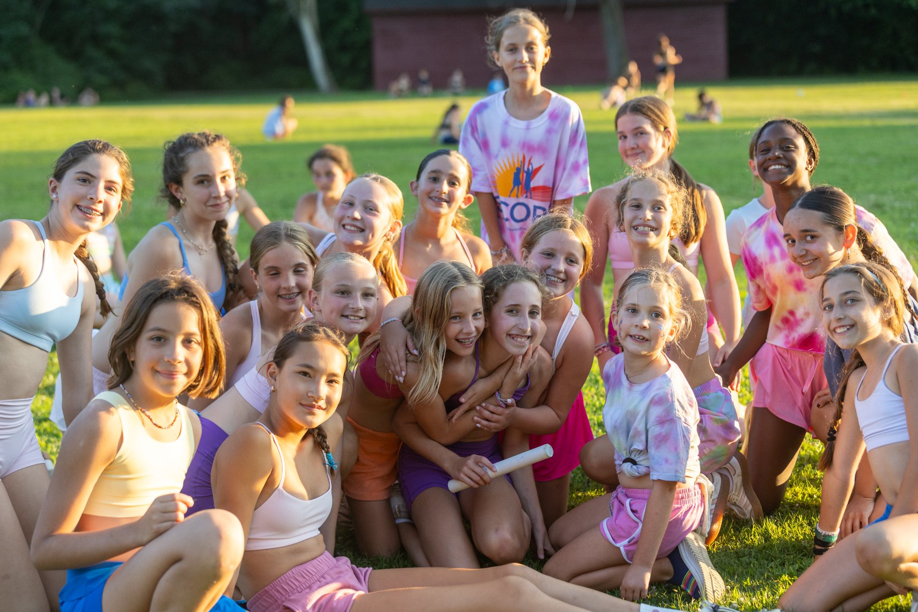 A large group of campers gathered together on the grass at the end of the day