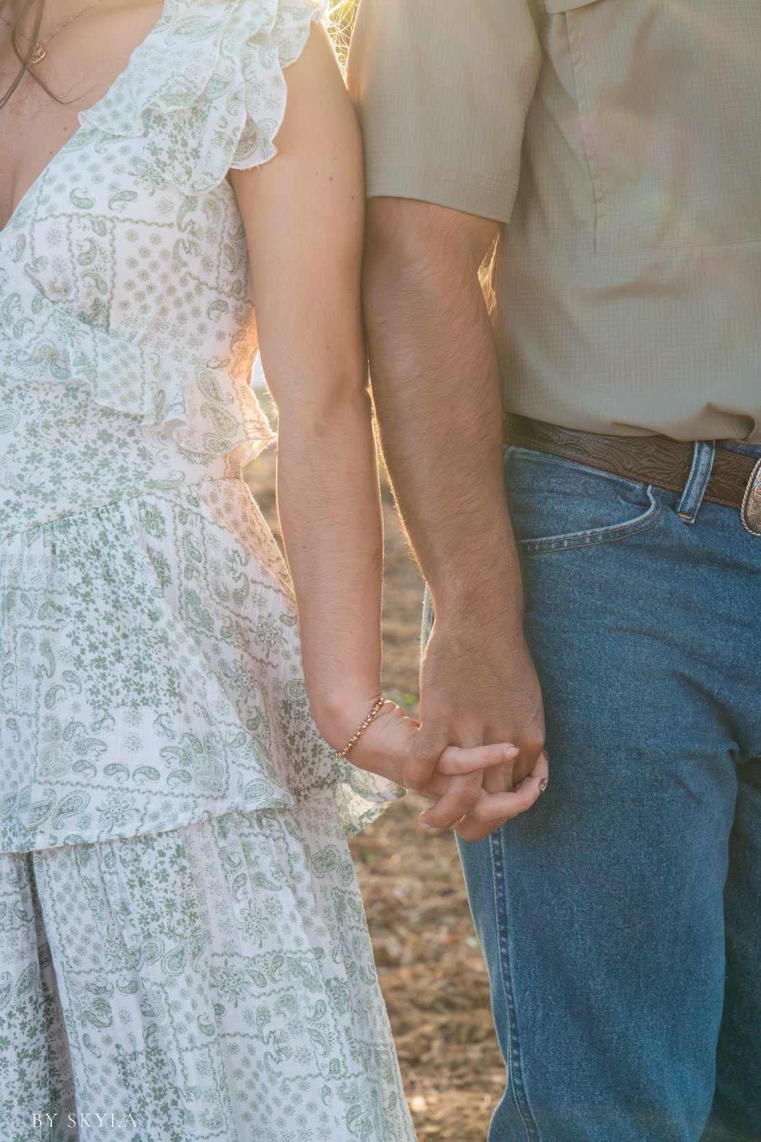 Close detail of a couple holding hands in golden backlight