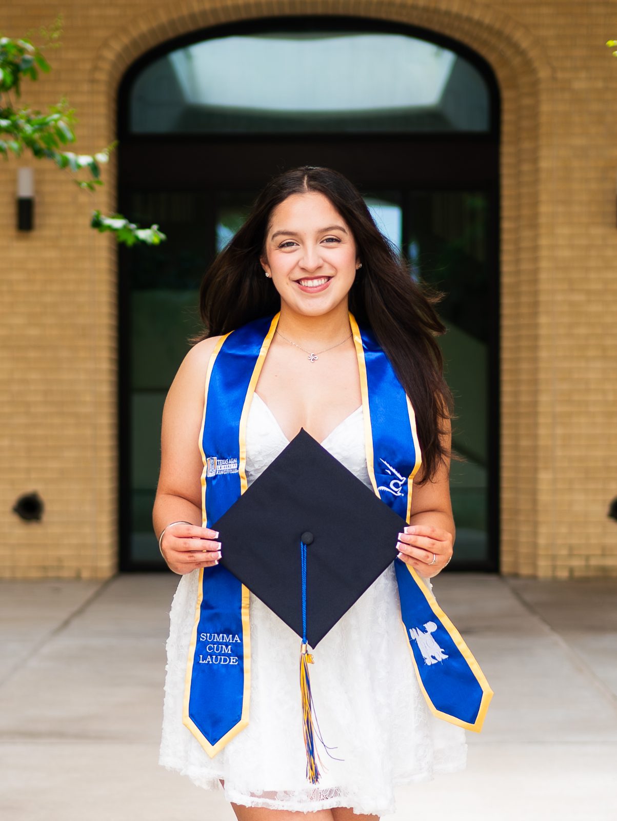 Graduate with a blue stole in front of a building