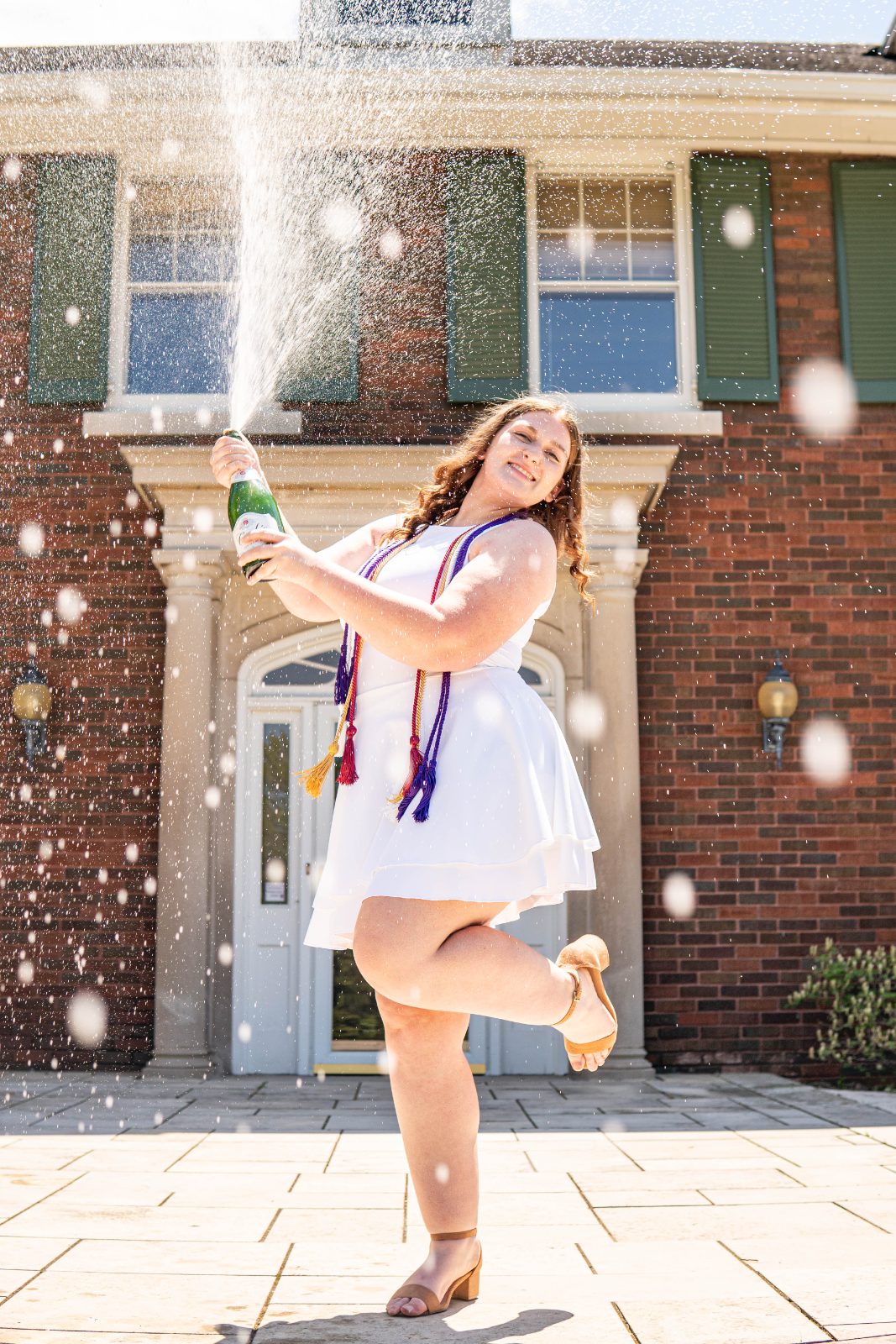 Graduate spraying champagne outside a campus building