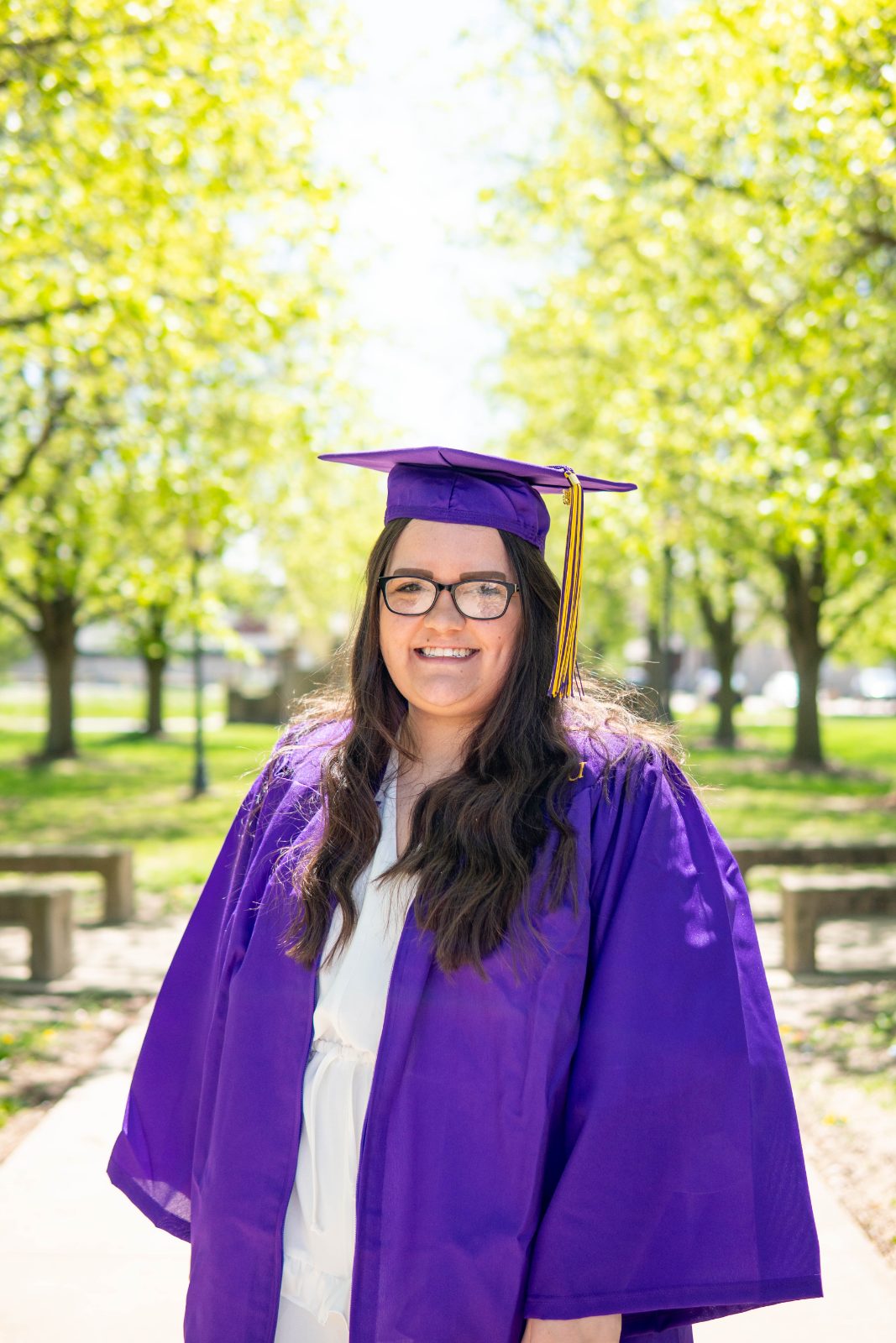 Graduate in a purple gown among spring trees