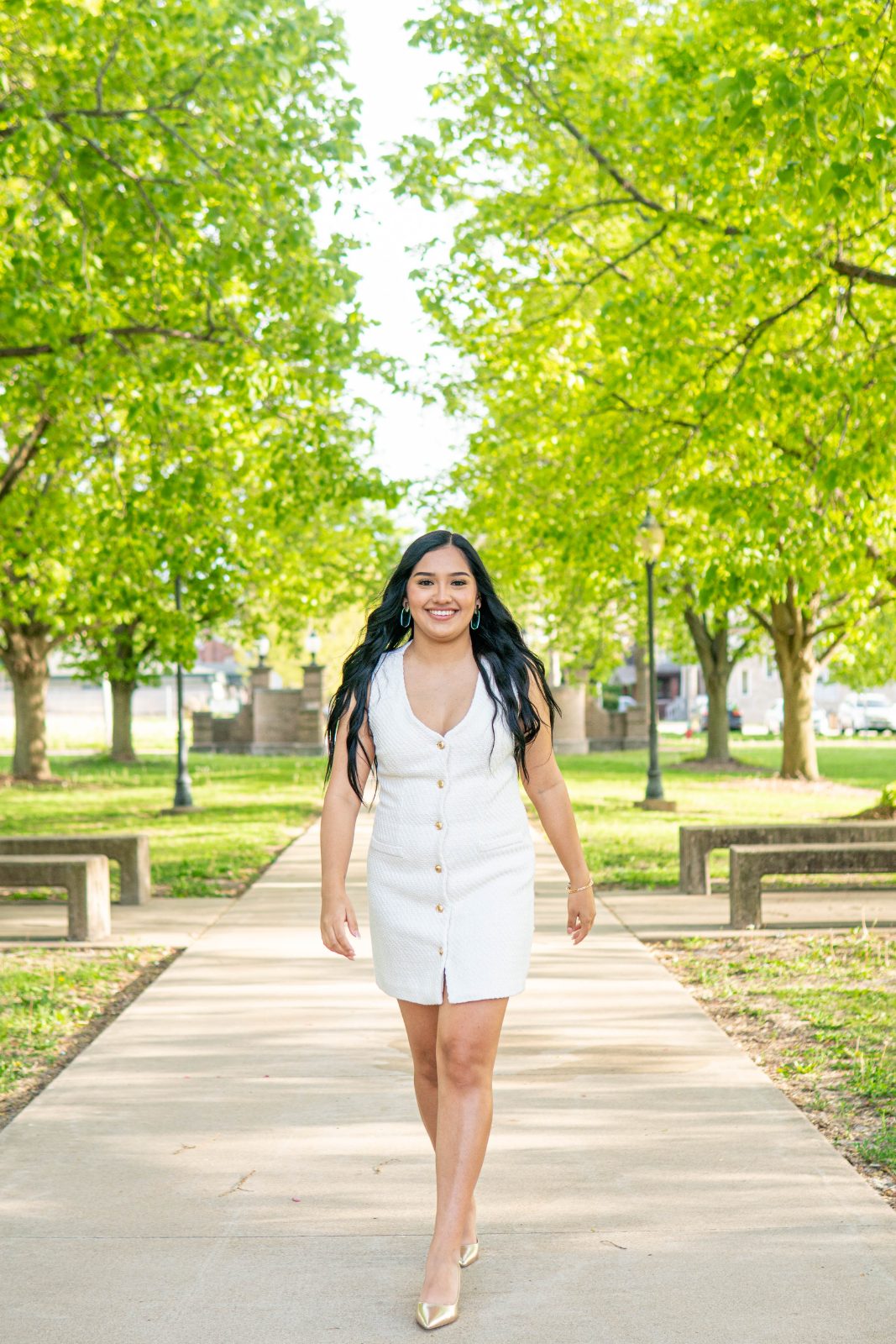 Graduate walking a tree-lined campus path