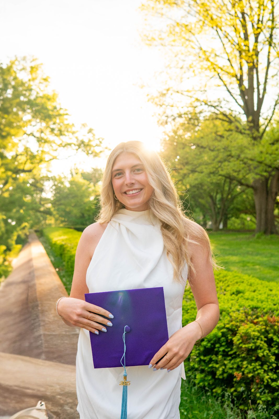 Graduate in a white dress holding her cap