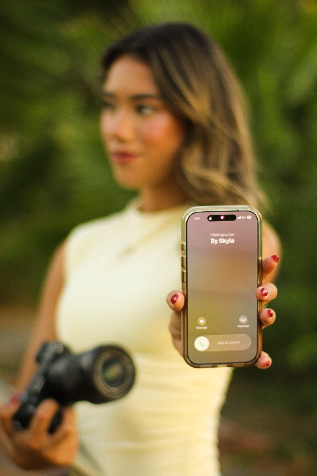 Mia holding a phone displaying Photographer By Skyla
