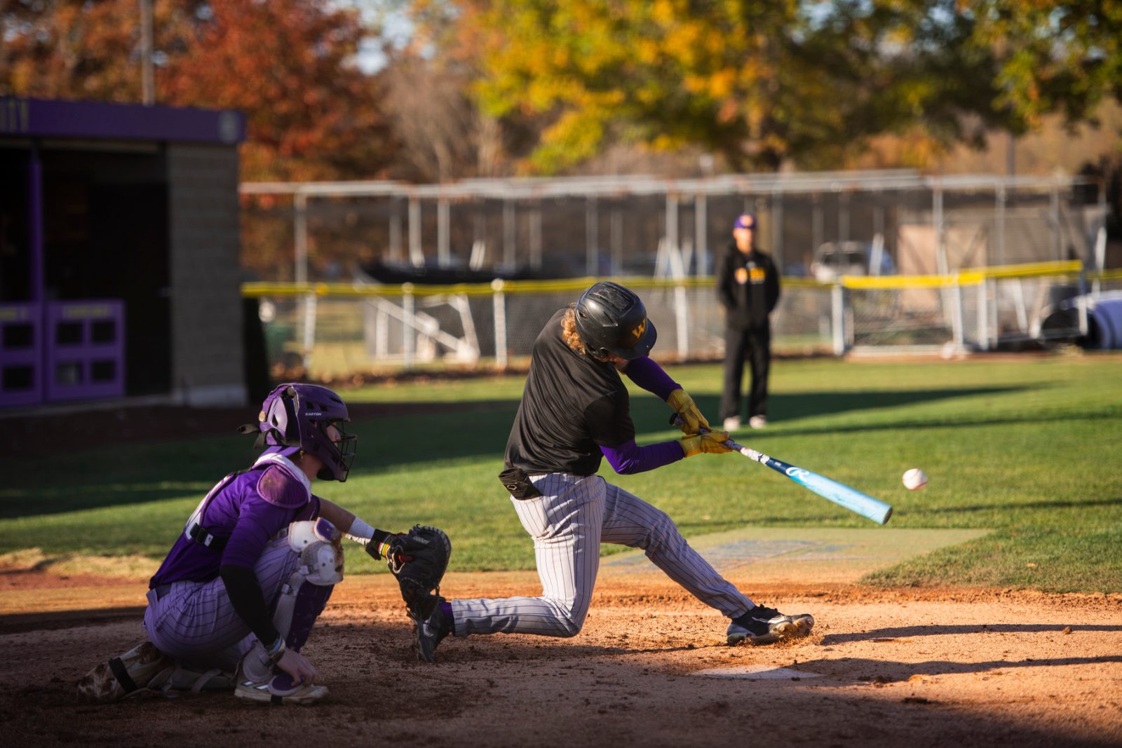 Baseball batter making contact in autumn light