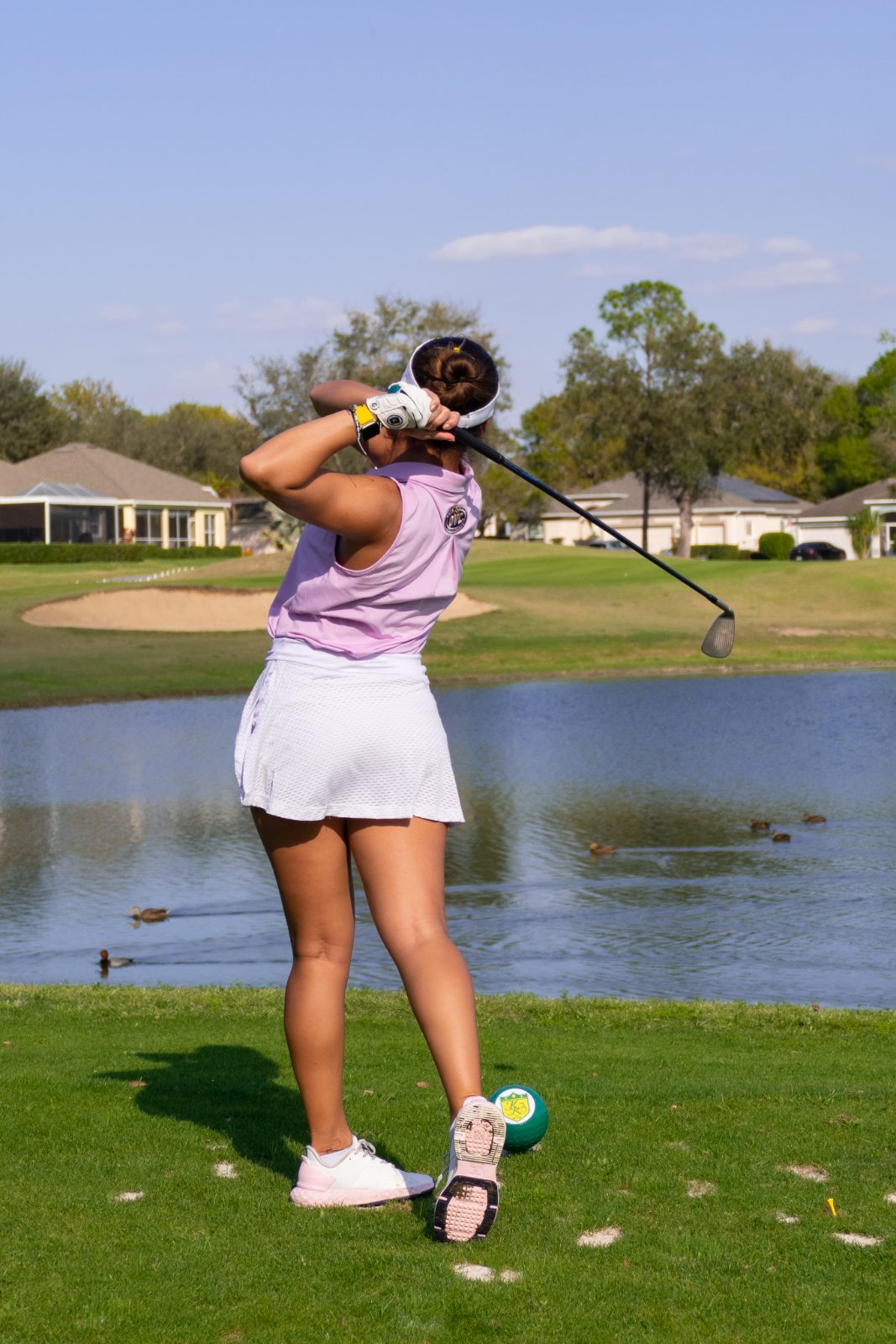 Golfer mid-swing beside water