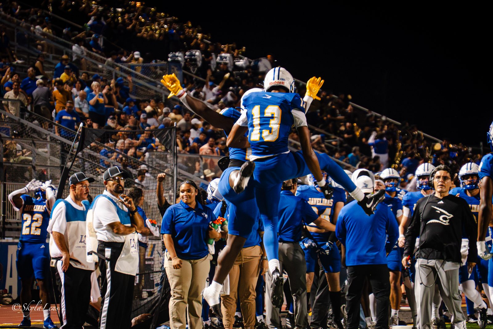 Football team running onto the field through a crowd